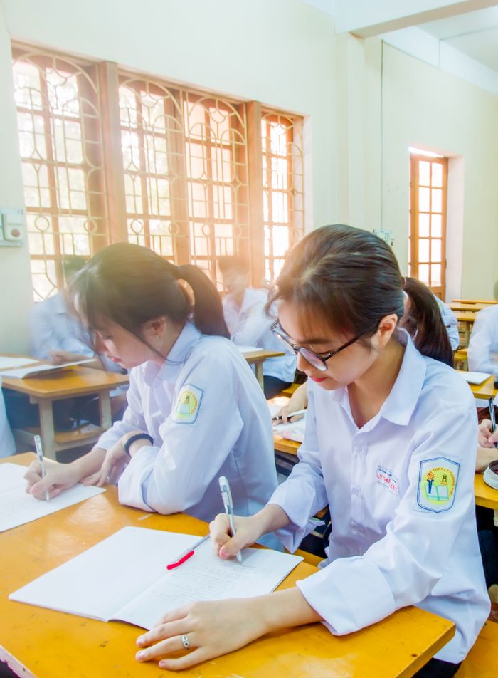 Asian schoolgirls focused on studying in a bright classroom setting.